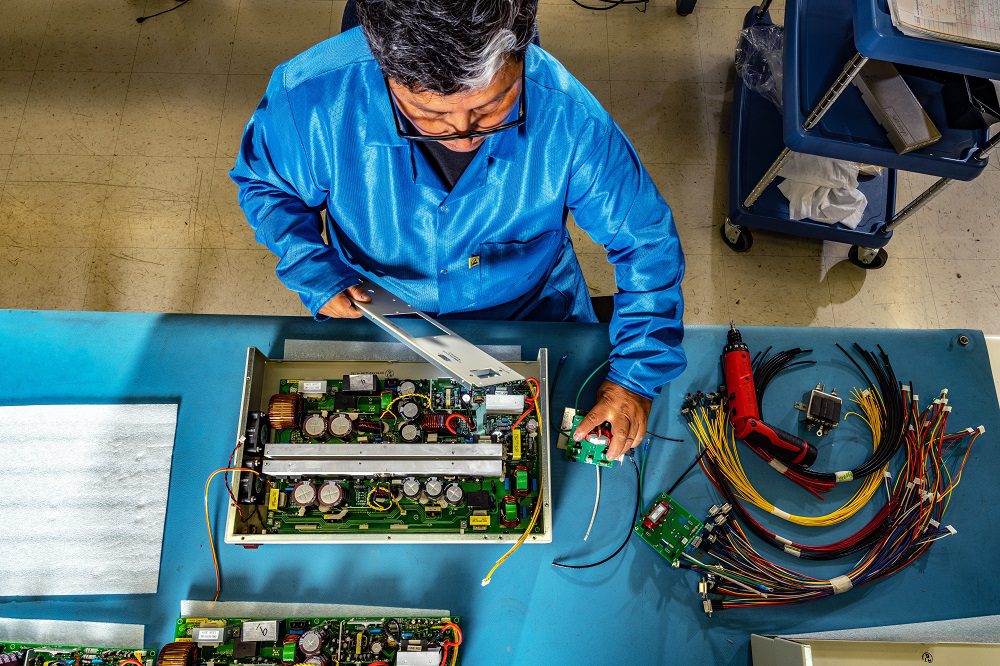 Technician working on electronic circuit board assembly.