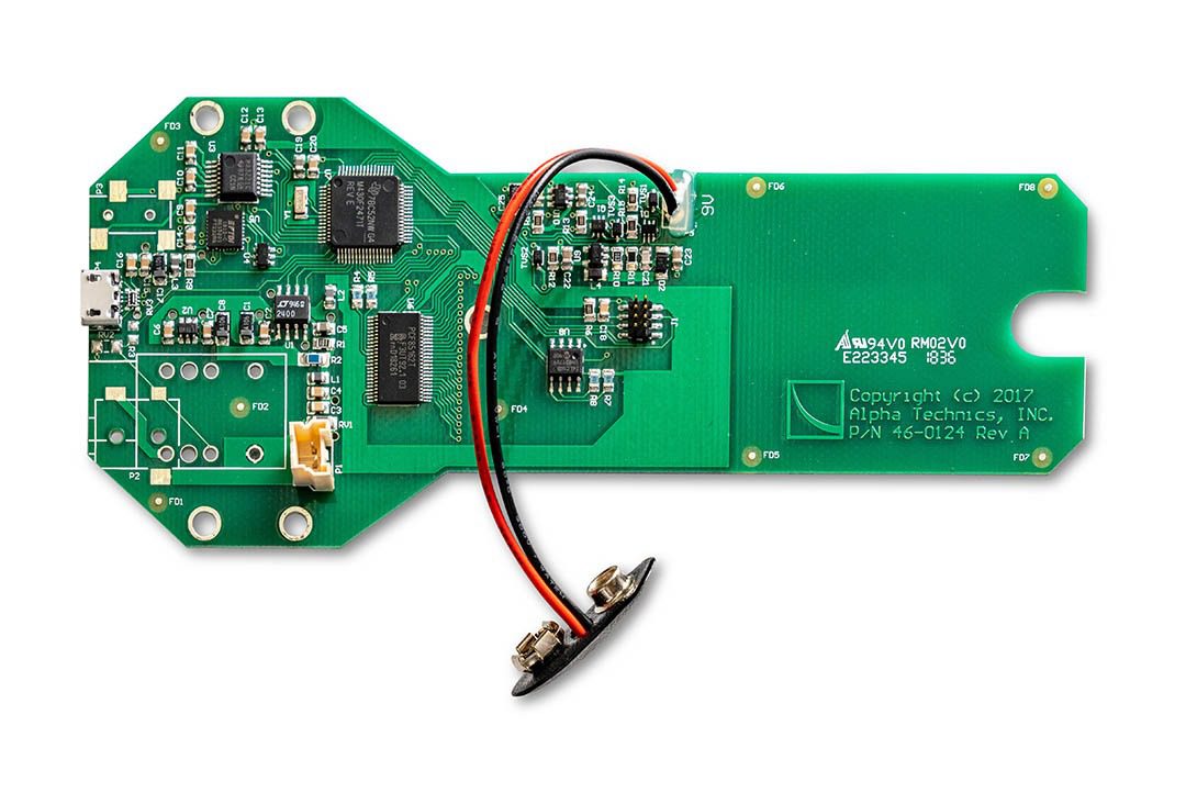 Green electronic circuit board with attached wires.