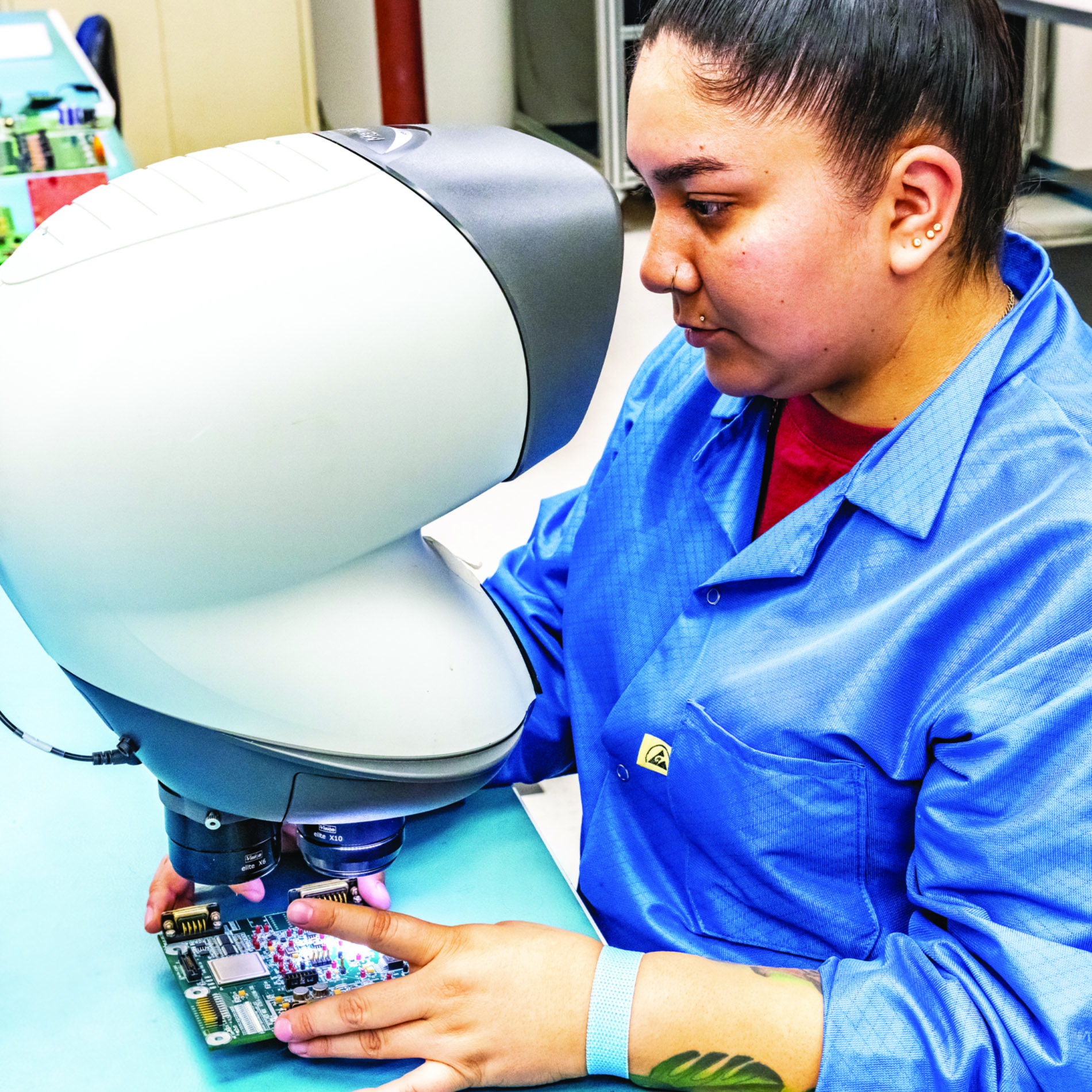 Technician inspecting circuit board under microscope