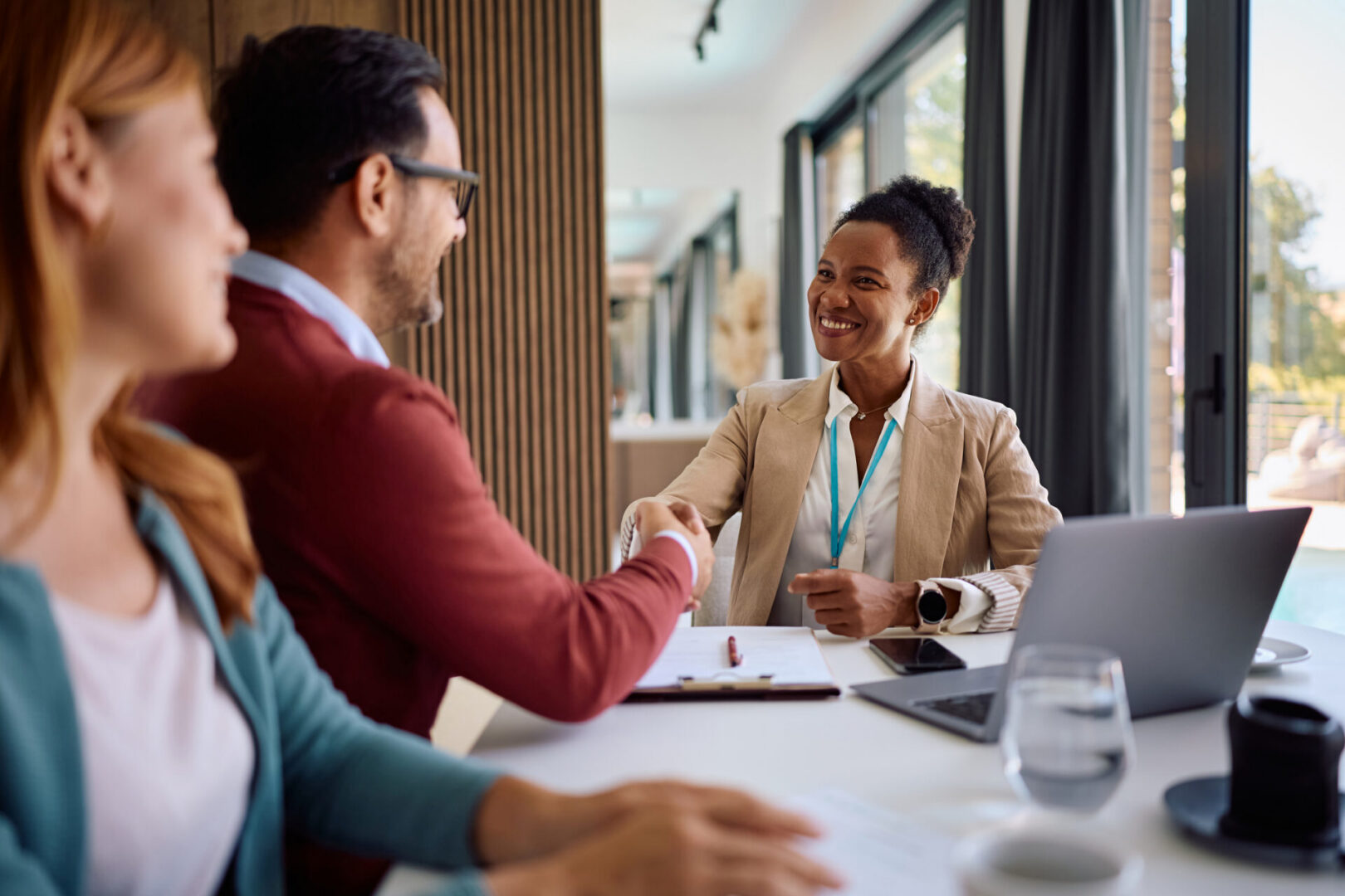 Happy African American insurance agent coming to an agreement her clients during a meeting.